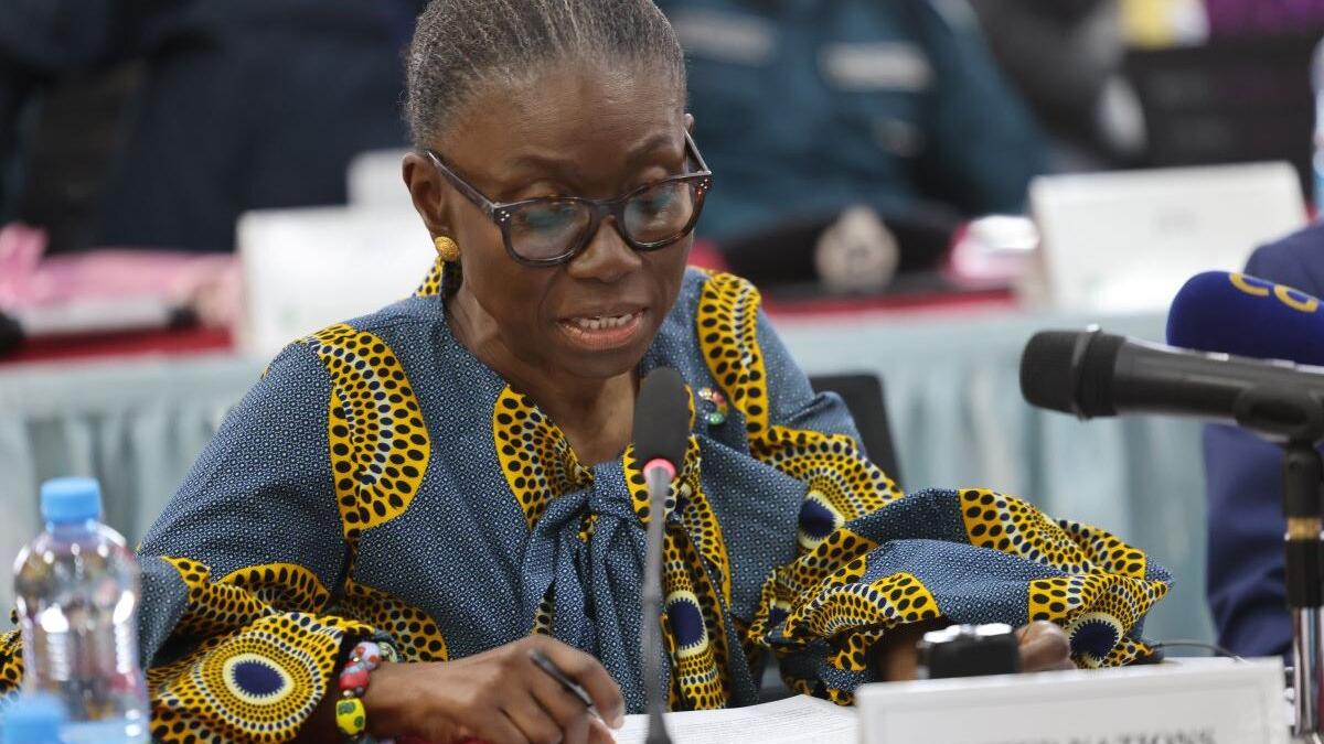 Ms. Anita Kiki Gbeho, Officer in Charge, SRSG and DSRSG-Resident/Humanitarian Coordinator seated at a conference table speaking into a microphone, wearing a patterned blue and yellow outfit, with documents and water bottle on the table.