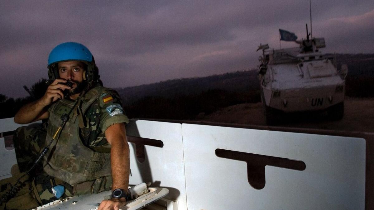 A peacekeeper uses radio equipment on a vehicle outside.