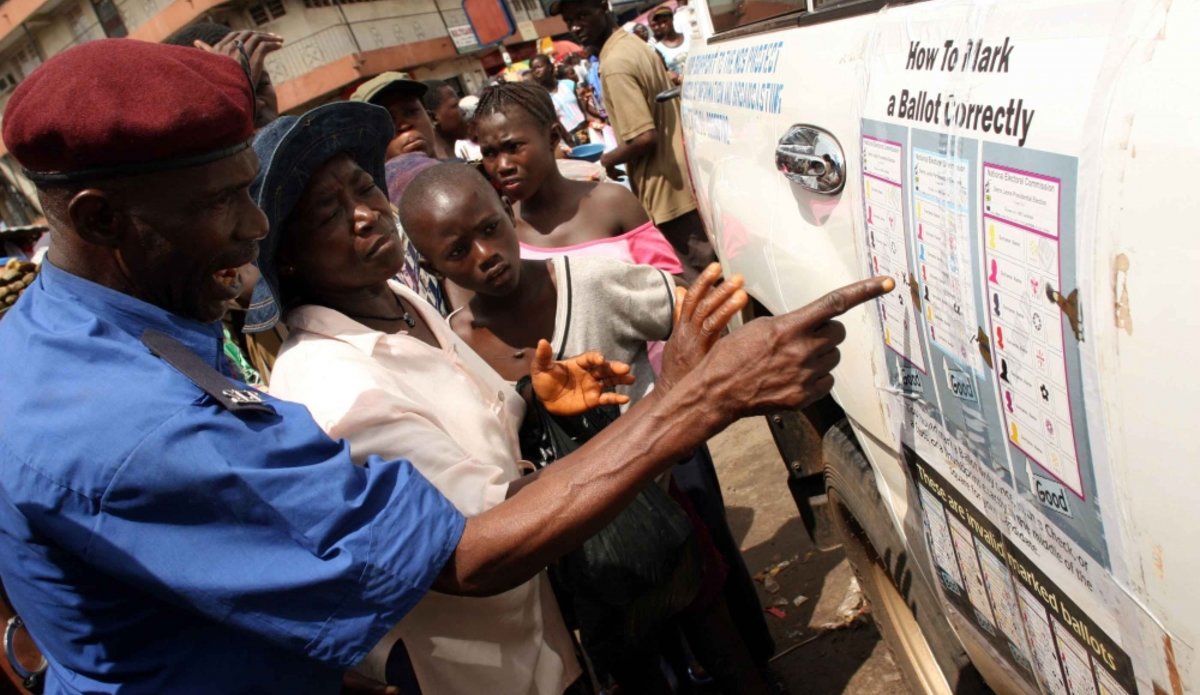 A policeman uses a poster to show a woman how to mark a ballot correctly in Freetown days ahead of the country’s presidential elections on 11 August 2007. Thanks to security forces, Sierra Leone organized, in 2007, violence-free election after 11 years of civil war. Credit: IRIN