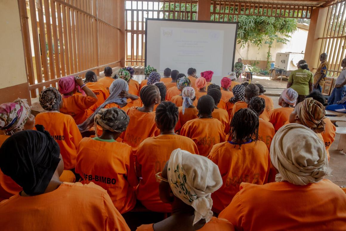 Un groupe de femmes en combinaisons orange regarde un écran