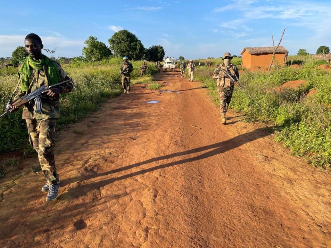 Un groupe d'hommes armés en uniforme militaire descend un chemin de terre